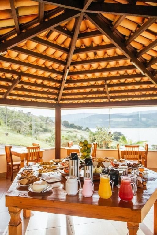 Refeitório envidraçado com a mesa do café e o lago ao fundo